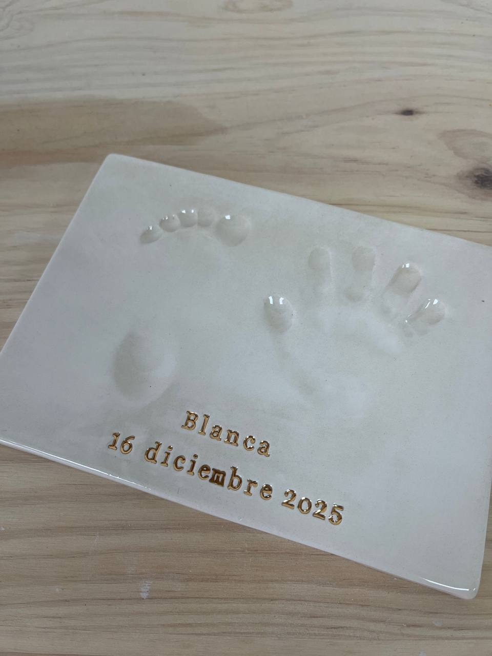 Detalle de placa artesanal de huellas con acabado de letras en oro